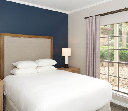 queen bed with 4 pillows beside window