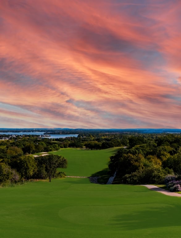 Red and orange sunset on a golf course overlooking the Texas Hill Country landscape.