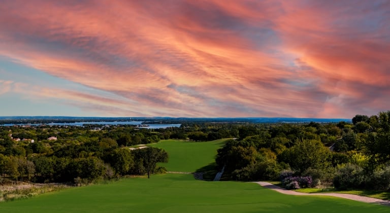 Red and orange sunset on a golf course overlooking the Texas Hill Country landscape.