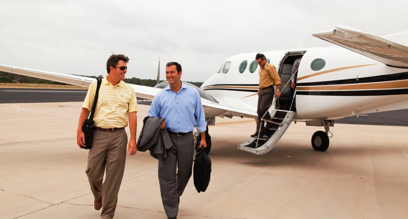 Two men walking off of the airstrip after a long day of travel.
