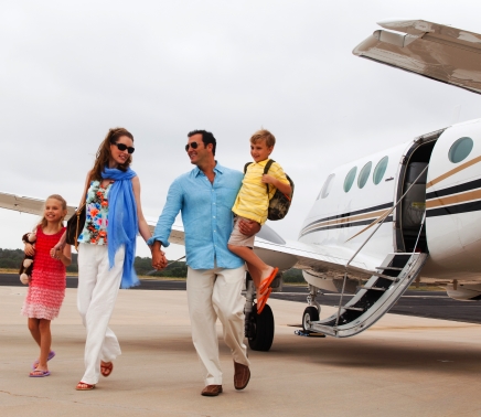 Family of four walking off of a private jet on the airstrip.