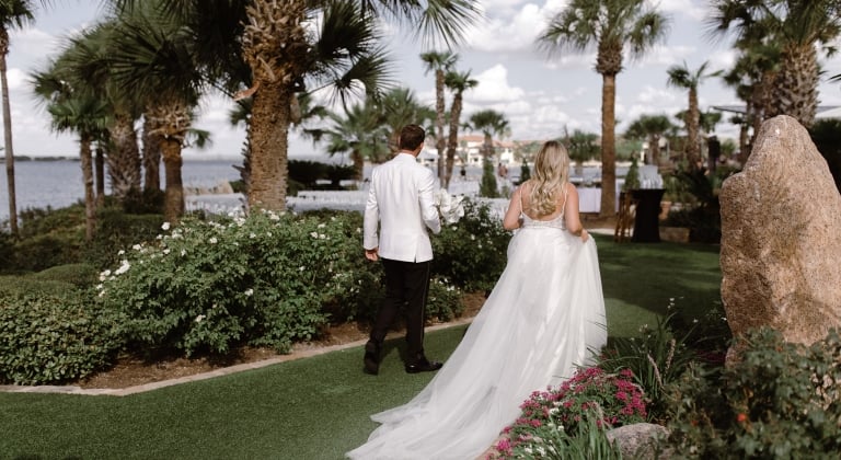 Couple walking after their ceremony. Palm trees and green grass as they walk to their after party.