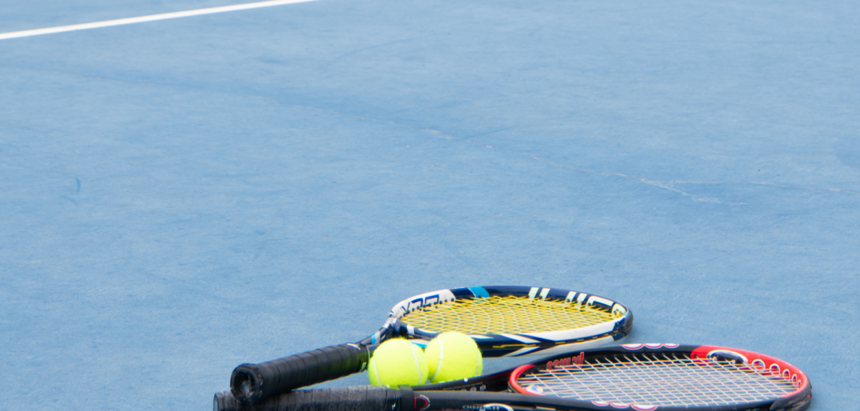 tennis court with rackets and two balls placed on court