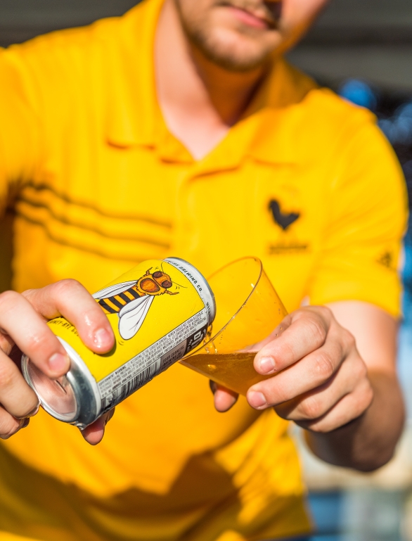 someone pouring beer into a cup with a image of a bee on the can