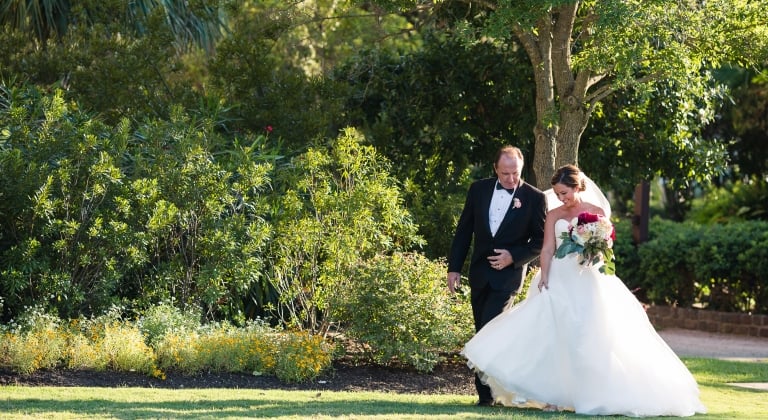 Father and Bride walking in the grass embracing one another