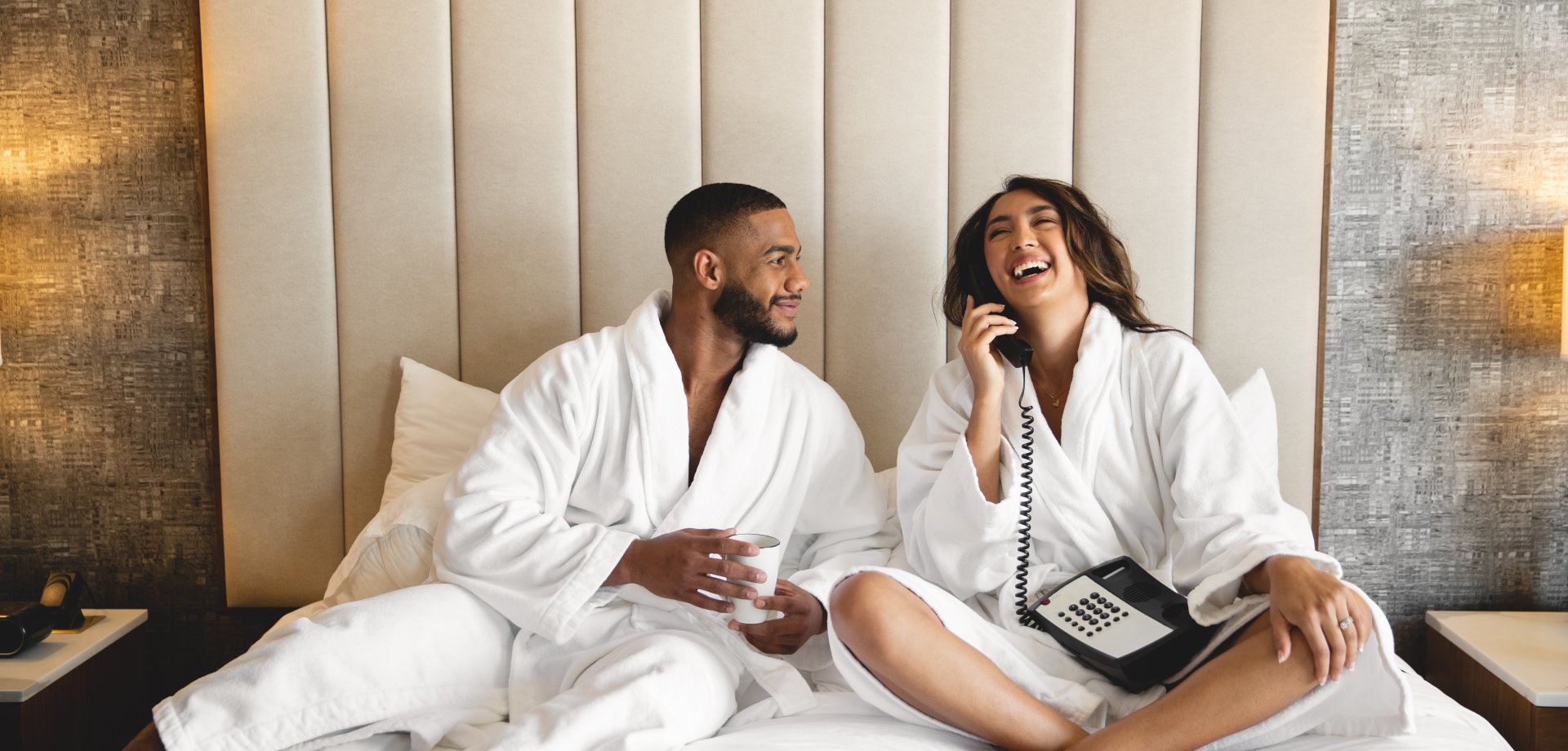 Couple sitting in bed in robes ordering room service
