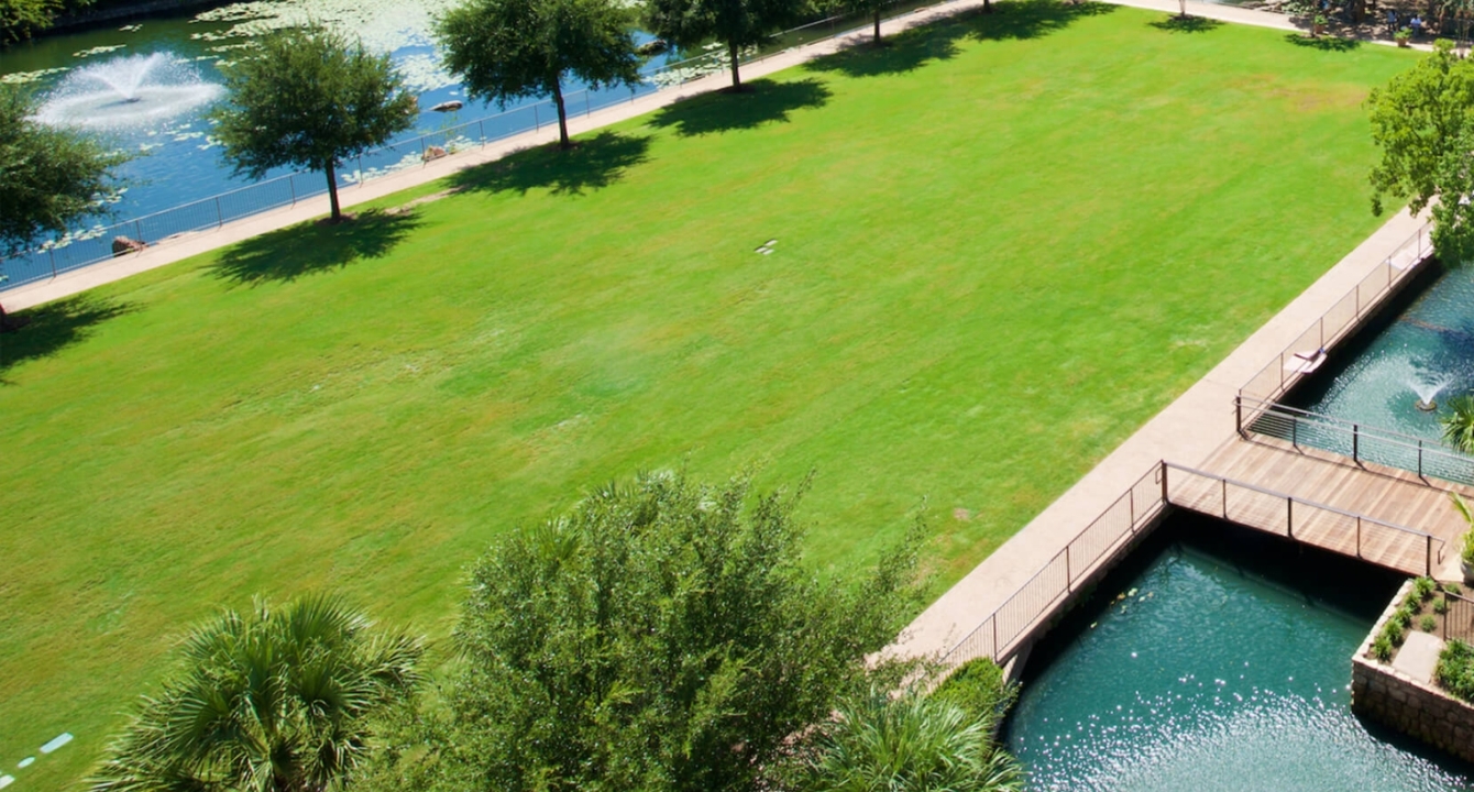 Large lawn of green grass for outdoor events and parties, ponds surrounding the grass.