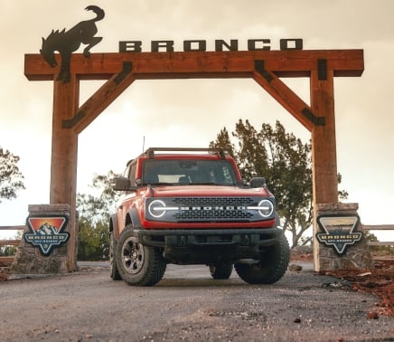 A red Bronco underneath a large wooden sign that reads Bronco.