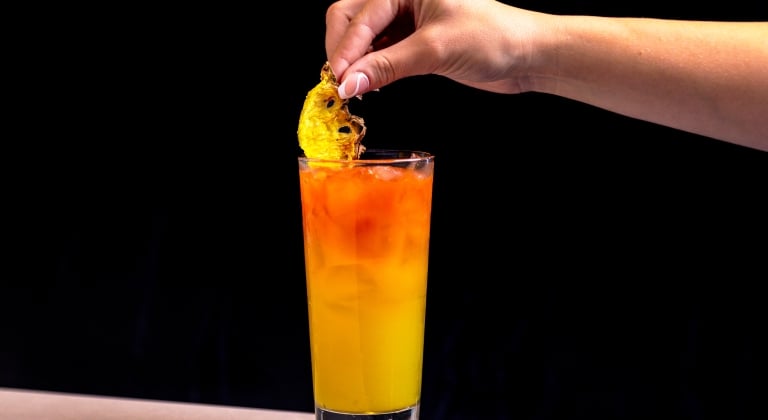 Orange and pinapple cocktail garnished with pineapple slices.