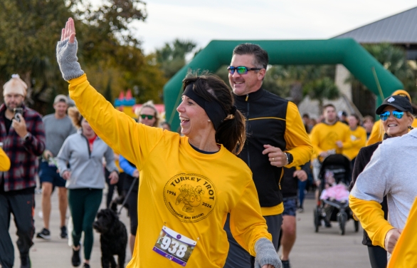 A woman waving while running in the Turkey Trot