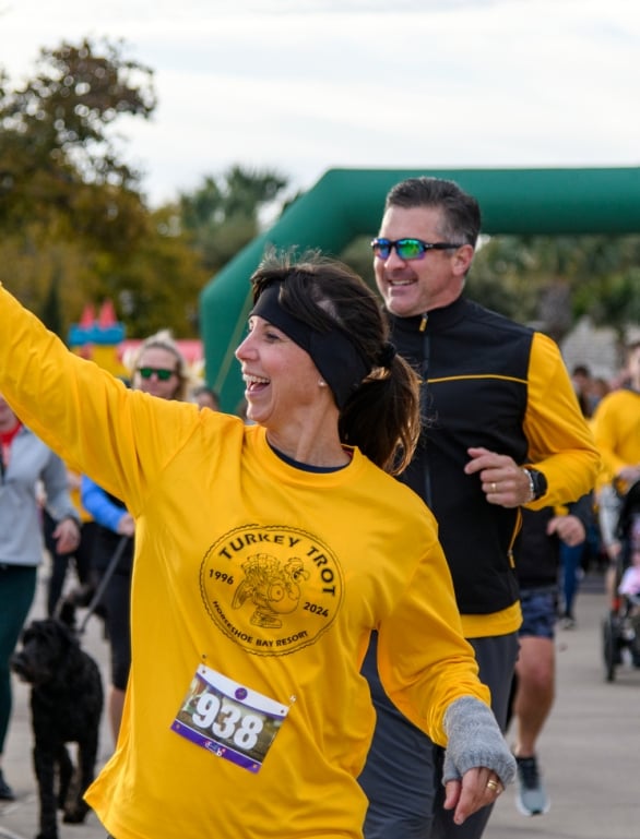 A woman waving while running in the Turkey Trot