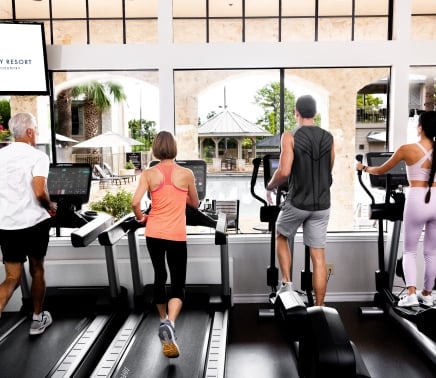Four people (2 men and 2 woman) on the treadmills at the gym.