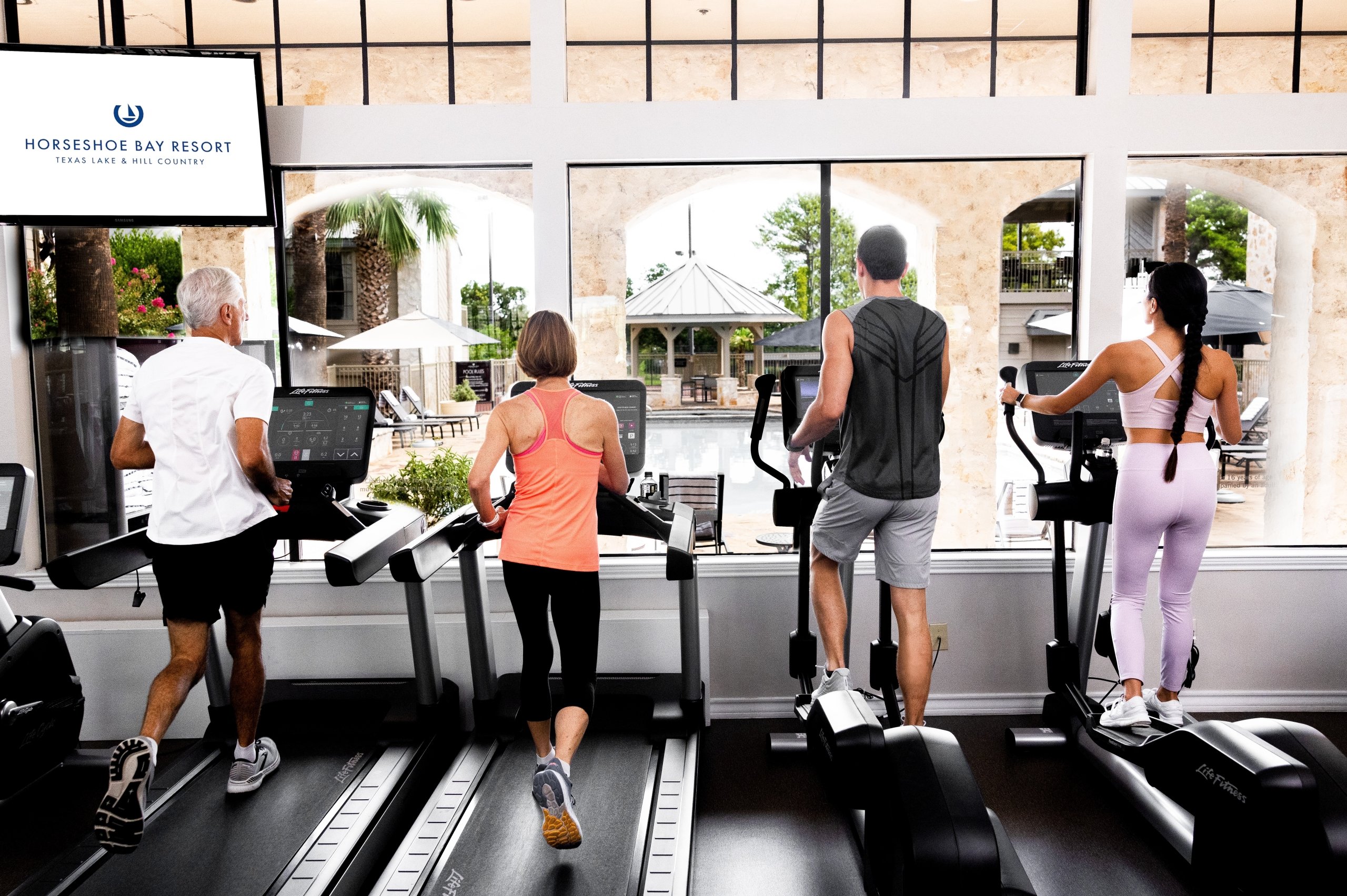 Four people (2 men and 2 woman) on the treadmills at the gym.