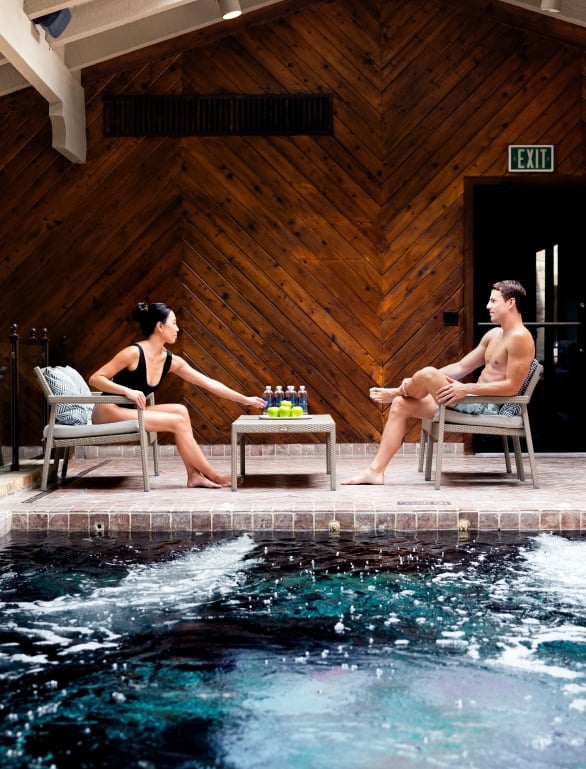 A man and a woman sitting by the indoor pool at the spa.