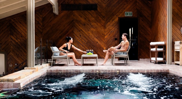 A man and a woman sitting by the indoor pool at the spa.