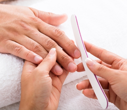 a man getting a manicure and his nails filed down.