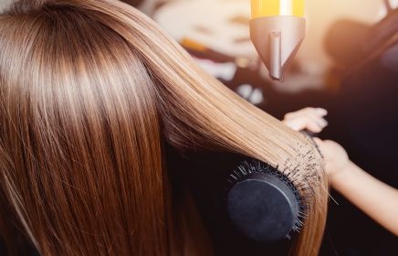 A hair stylist doing a blowout on a client.