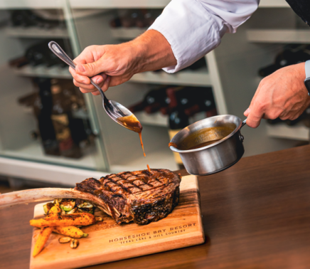 Chef glazing large steak in the kitchen.