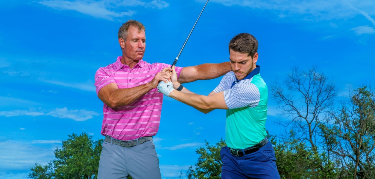 Golf instructor gving lesson to male player