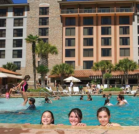 Three girls on the edge of the pool smiling.