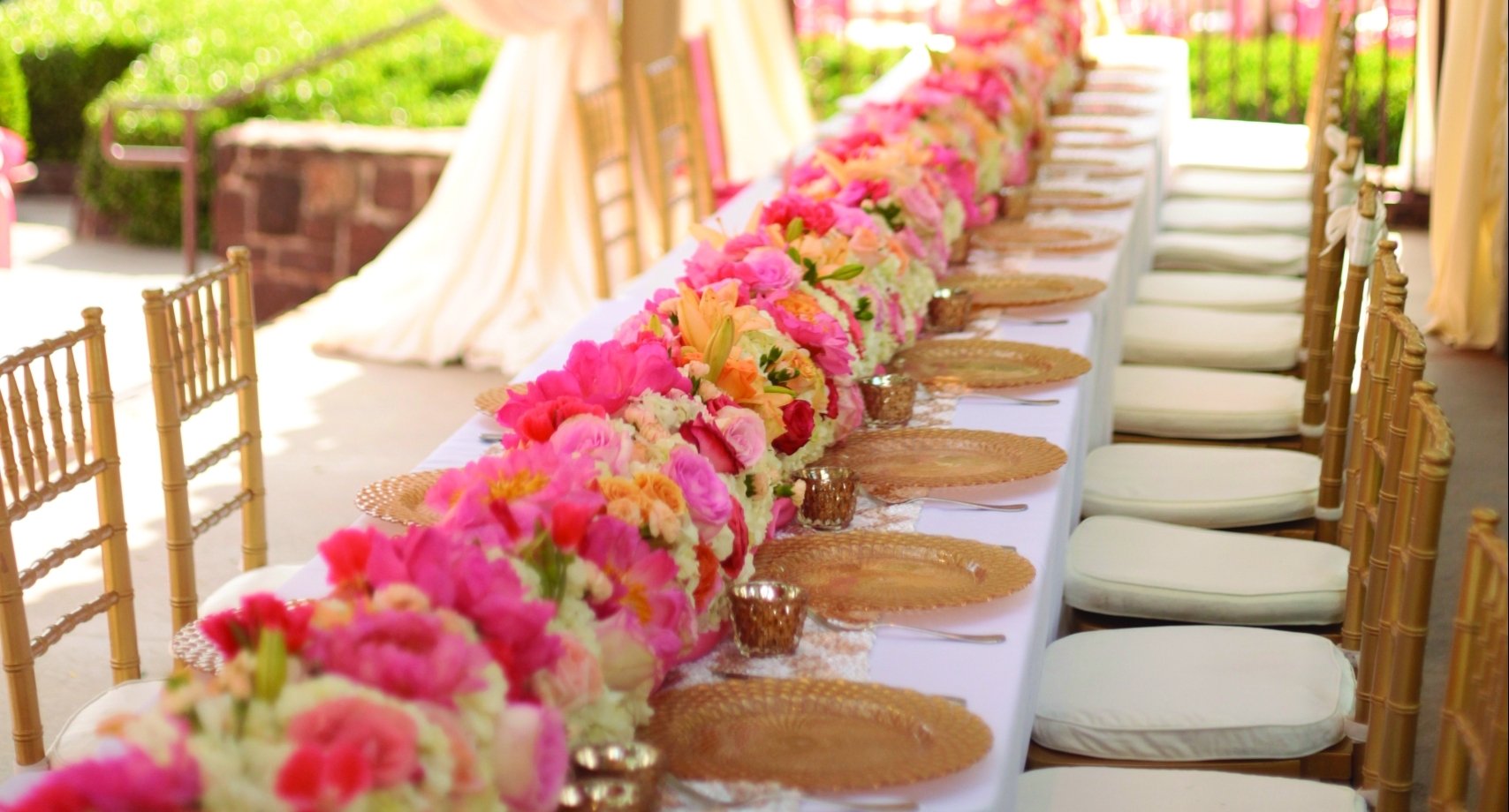 Pink and yellow flowers line the long table for the wedding party