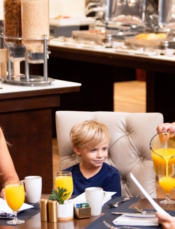 Serving pouring orange juice in family restaurant
