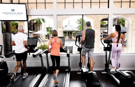 Four people (2 men and 2 woman) on the treadmills at the gym.