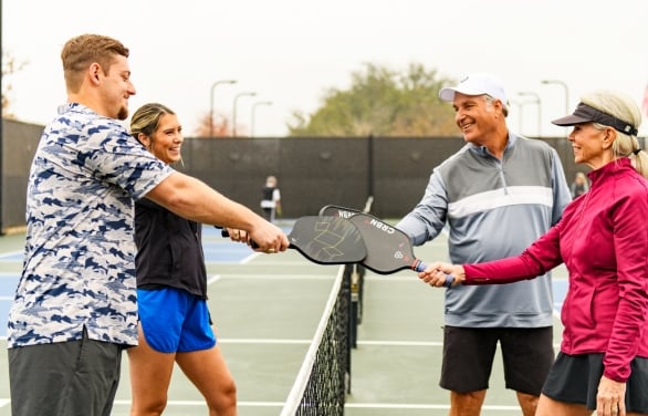A young and older couple playing Pickle Ball at Horseshoe Bay Resort