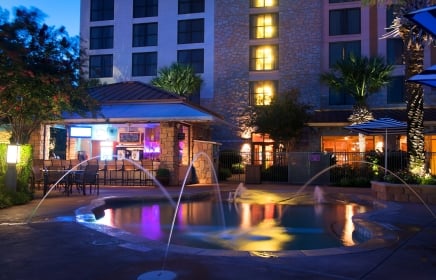 View of hotel pool with water shooting up for design in the dusk light.