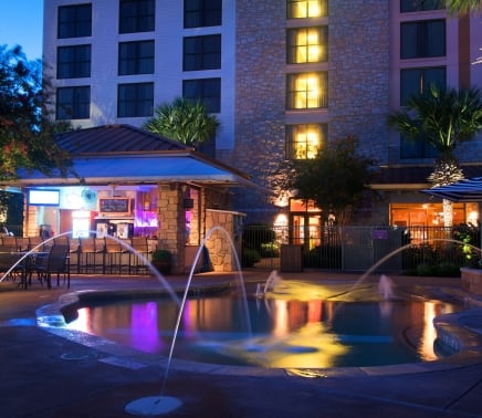 View of hotel pool with water shooting up for design in the dusk light.