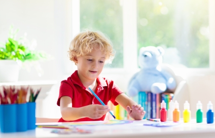 little boy painting with a paint brush in a craft room at horseshoe bay Texas jungle kids club